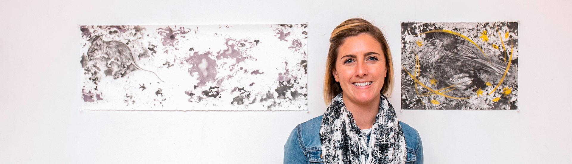 young woman with short hair in front of two paintings